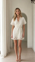 Model wearing white lace trim wrap mini dress front view