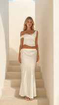 Front view of woman wearing white satin lace-trim crop top and midi skirt set on stairs