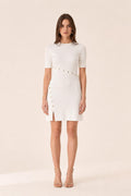 Front view of woman wearing white ribbed knit mini dress with gold buttons
