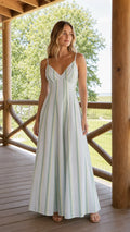 Front view of woman wearing white striped V-neck maxi dress on a wooden porch