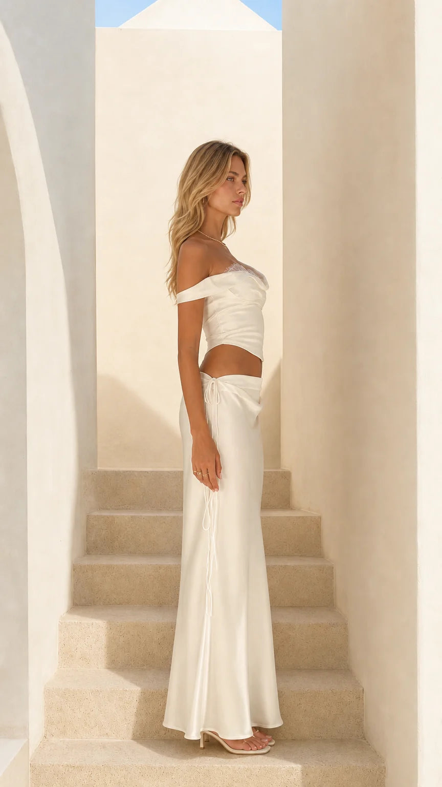Side profile view of woman in white satin two-piece outfit