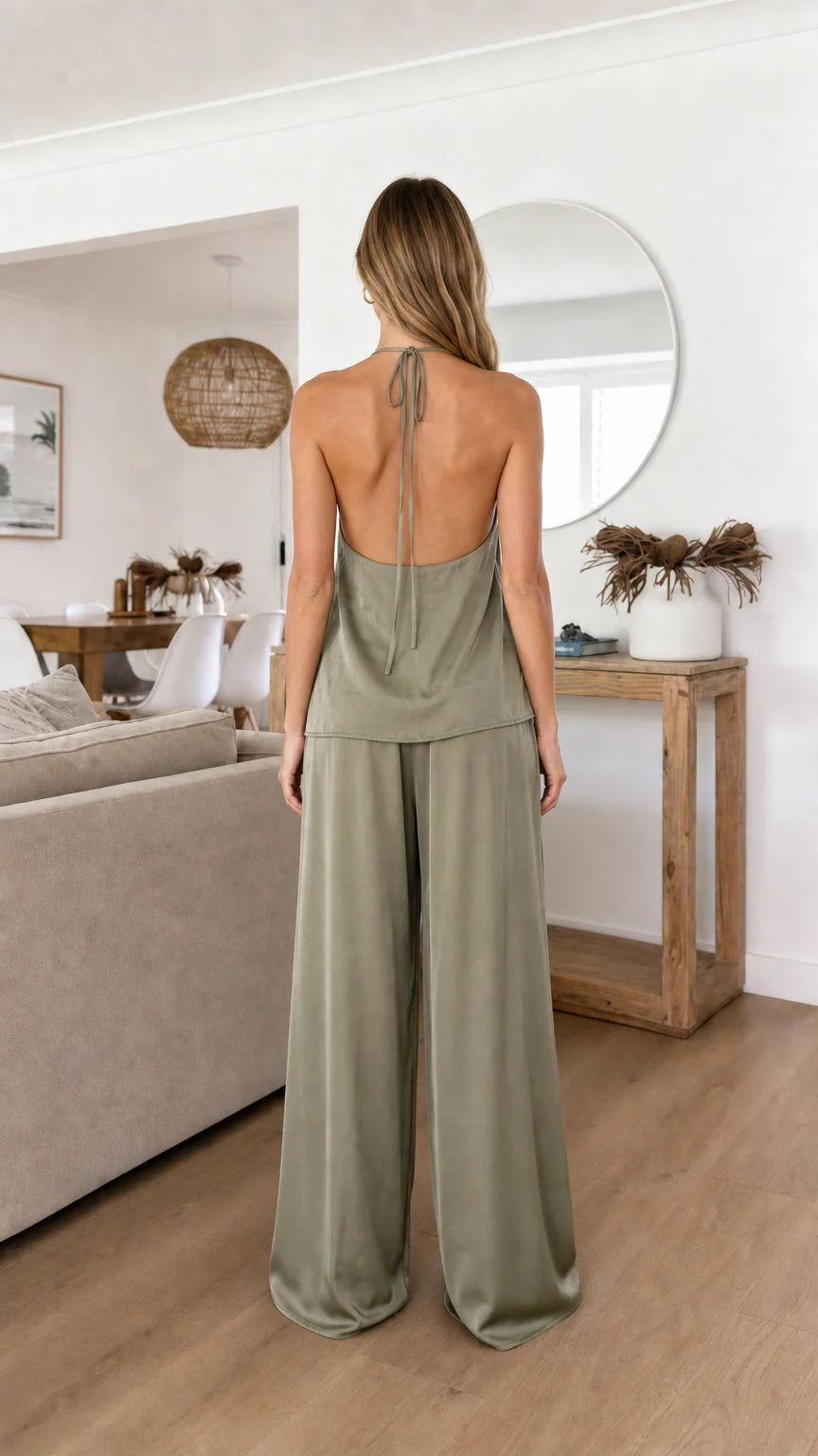 Back view of model in sage green satin halter top and trousers