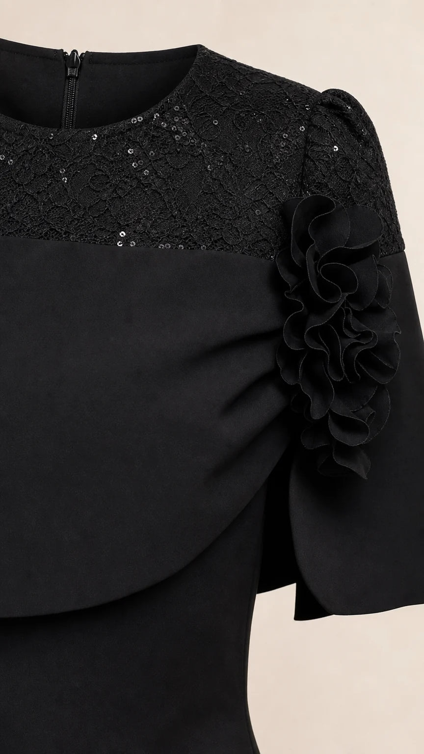 Close-up detail of black dress bodice showing sequin lace and floral applique