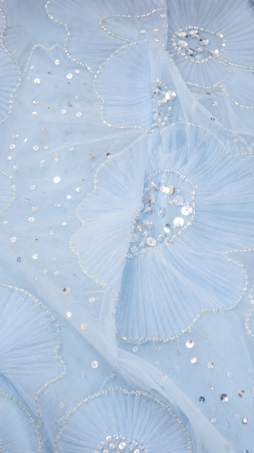 Close-up of light blue mesh fabric with sequin floral embroidery