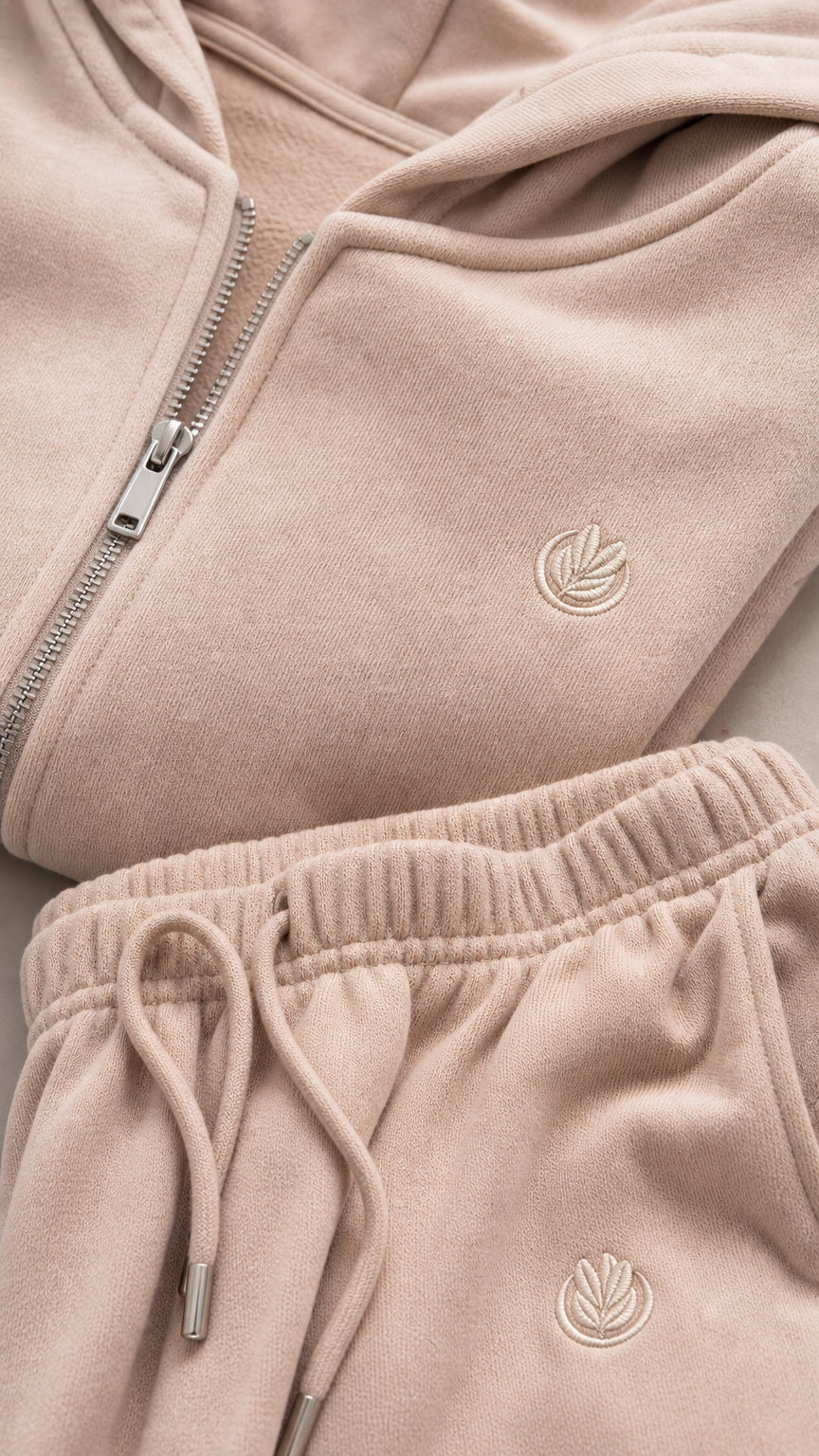 Close-up of beige hoodie zipper, hood, tonal detail, and drawstring pants