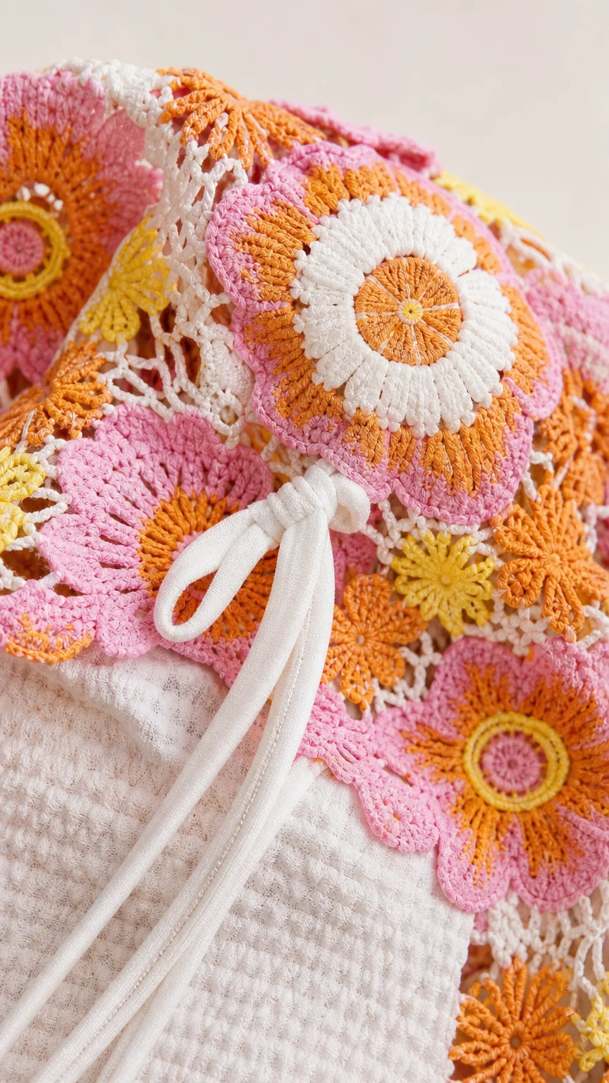 Close-up detail of white adjustable string and pink floral crochet texture