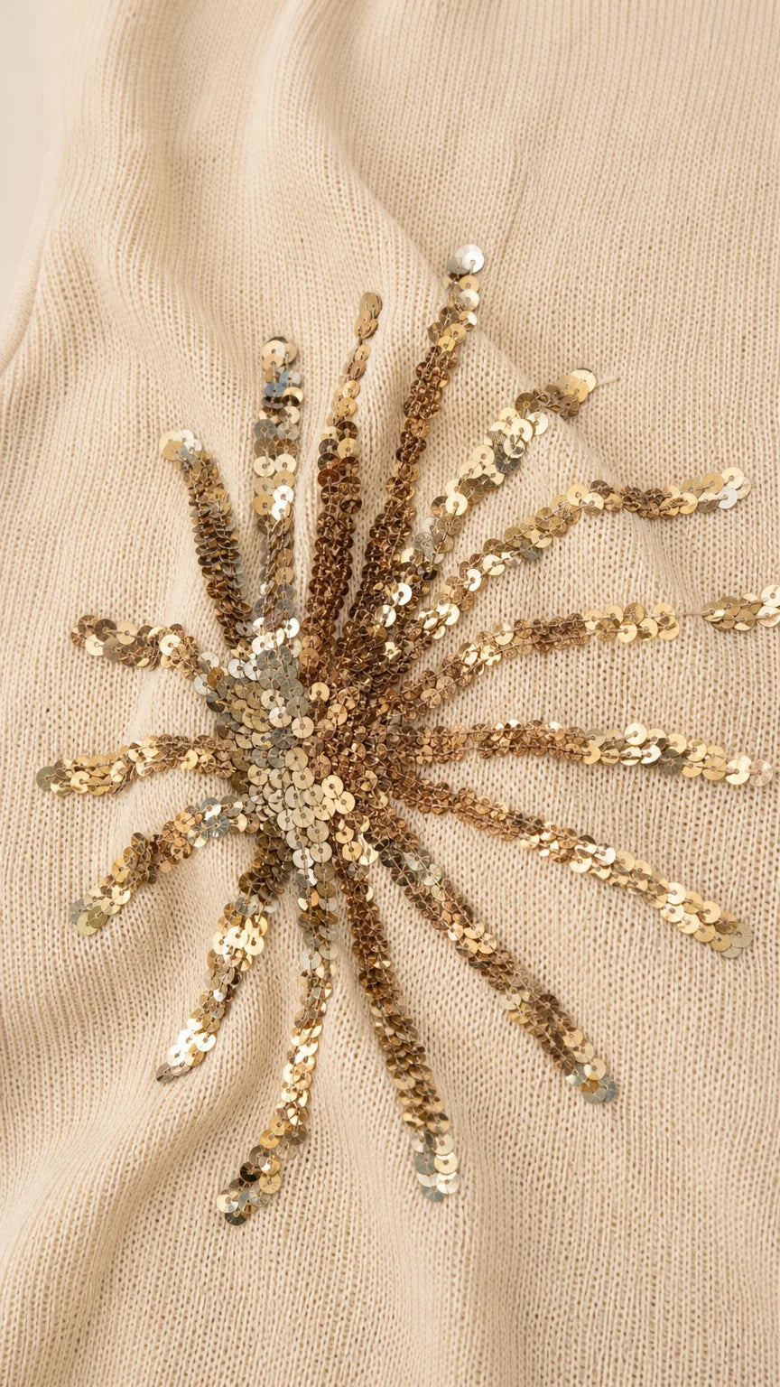 Close-up detail of gold sequin sunburst embroidery on fabric