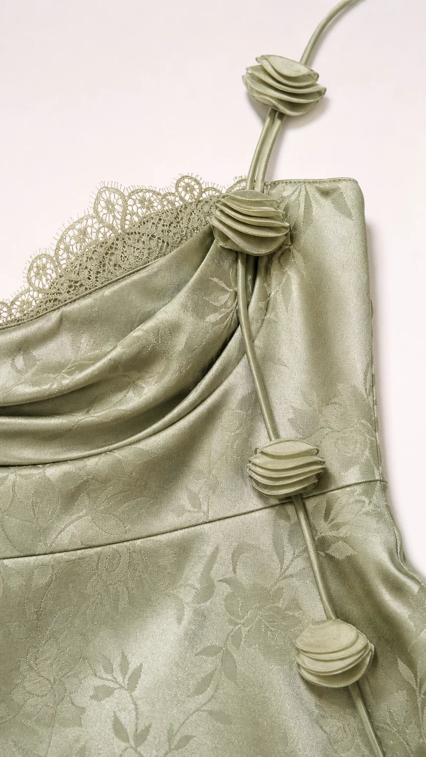 Close-up of rosette strap and lace detail on sage green dress