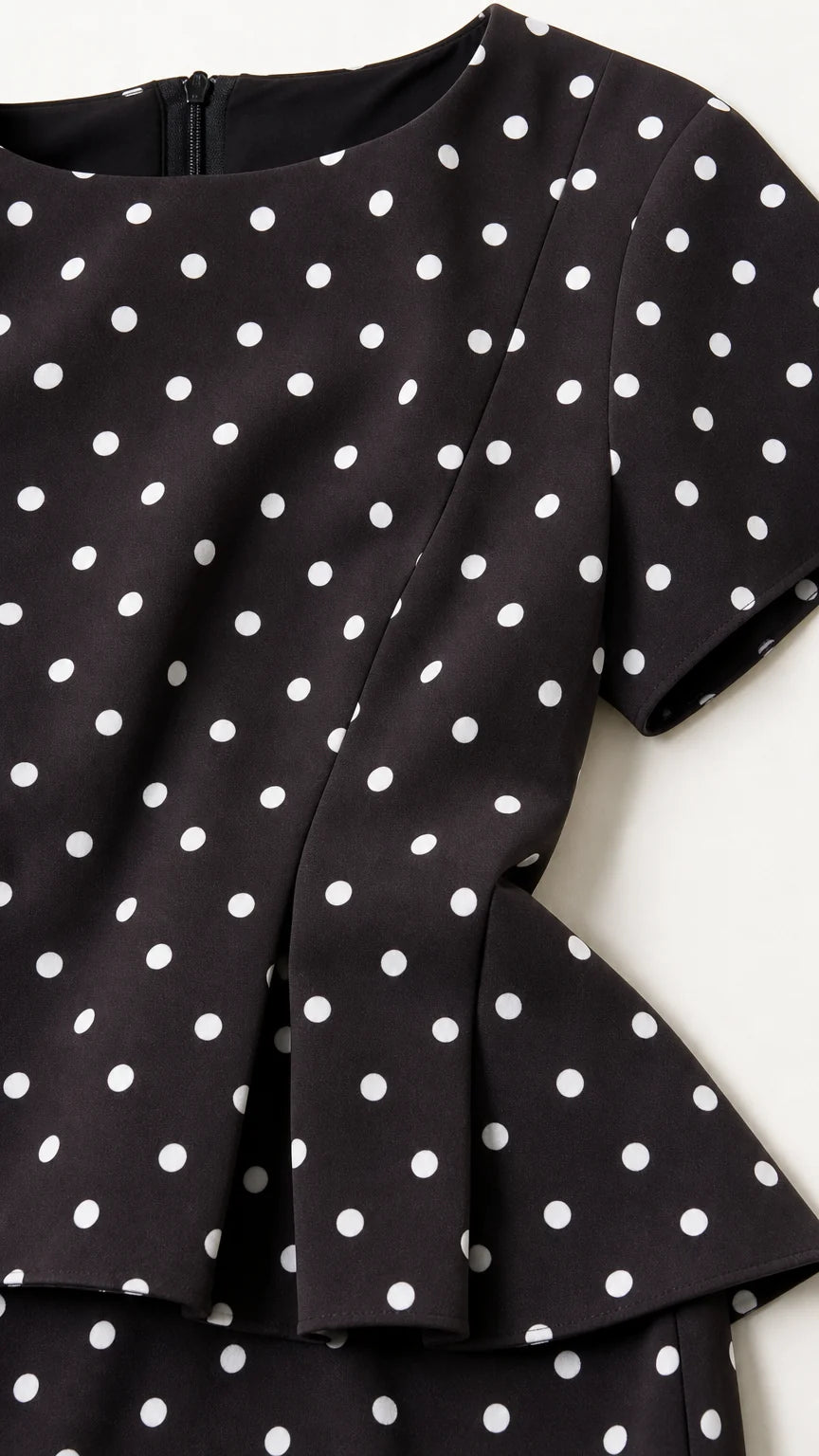 Close up detail of black polka dot fabric and peplum hem