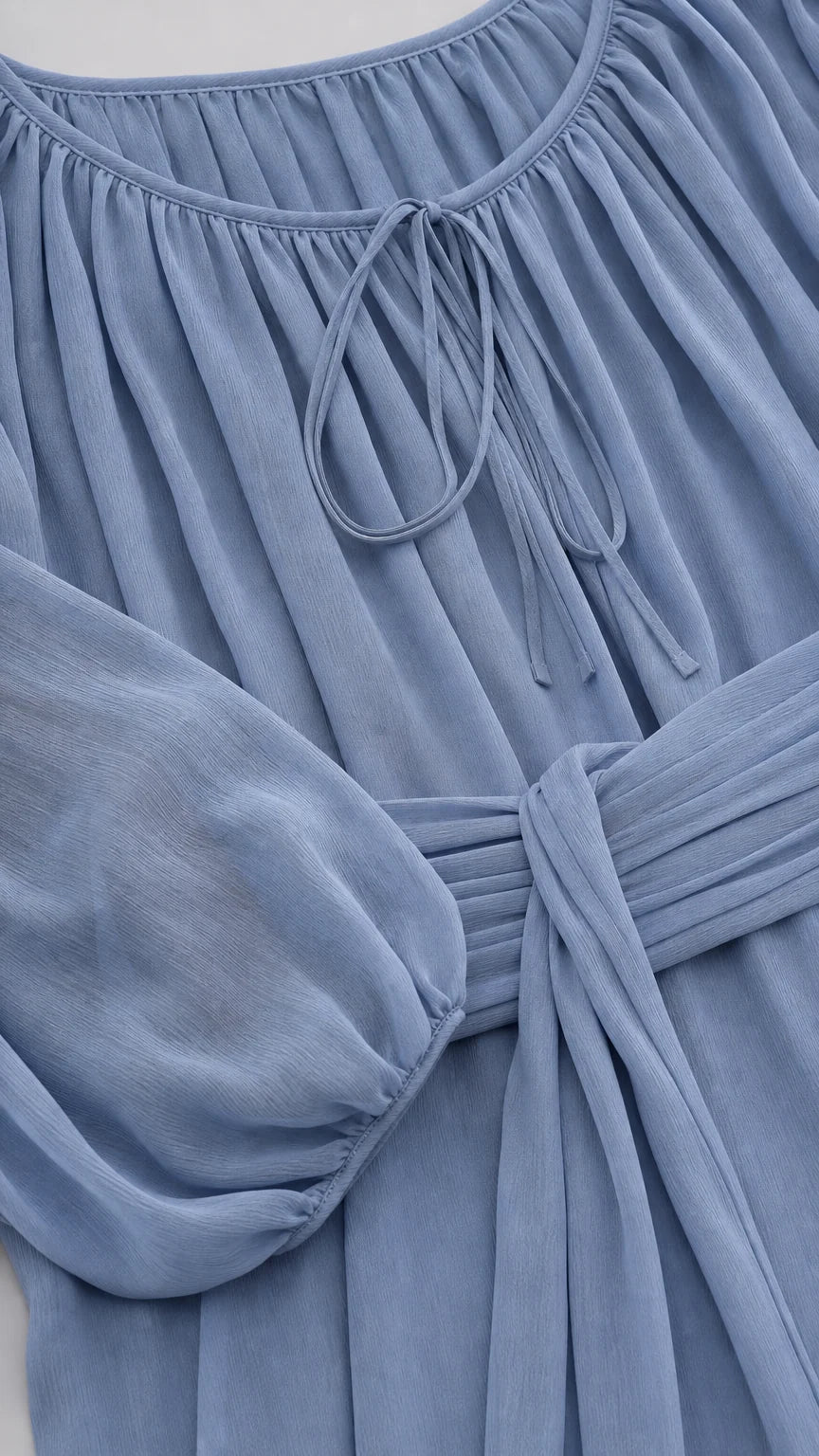Close-up detail of neckline and pleated waist tie on blue midi dress